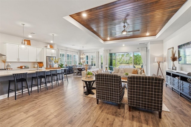 living room featuring a tray ceiling, a wealth of natural light, wood finished floors, and wooden ceiling