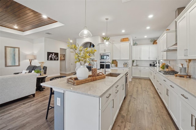 kitchen featuring backsplash, a breakfast bar, appliances with stainless steel finishes, light wood-style floors, and a sink