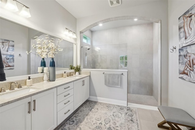 bathroom featuring double vanity, a walk in shower, visible vents, and a sink