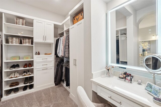 walk in closet featuring arched walkways and light carpet