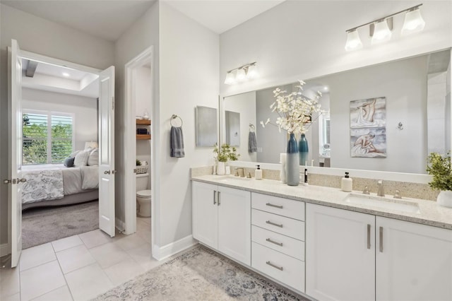 ensuite bathroom with double vanity, toilet, tile patterned floors, and a sink