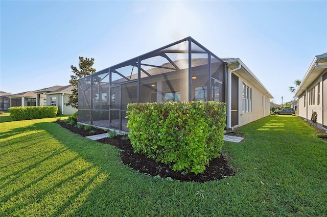 rear view of property featuring glass enclosure, a yard, and stucco siding