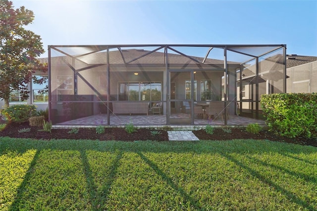 rear view of house featuring stucco siding, a lawn, glass enclosure, and a patio