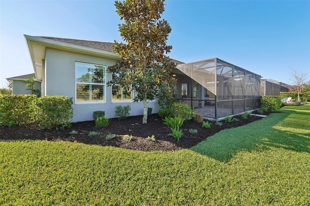 back of property featuring a lanai, a yard, and stucco siding