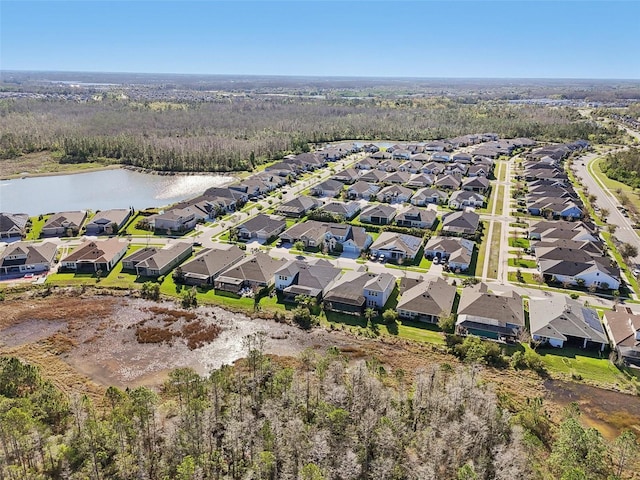 drone / aerial view with a wooded view, a residential view, and a water view