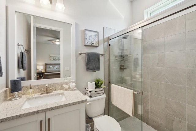 bathroom with toilet, a stall shower, vanity, and ceiling fan