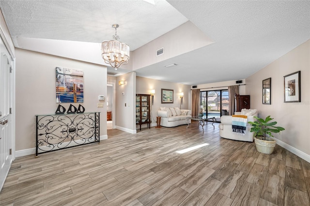 interior space featuring a notable chandelier, visible vents, light wood-type flooring, and baseboards