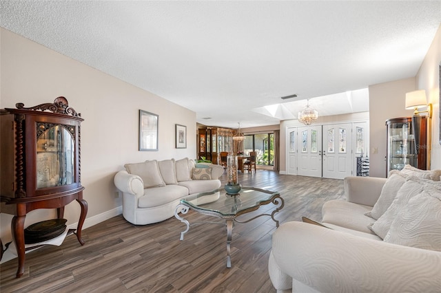 living room with a notable chandelier, baseboards, visible vents, and wood finished floors