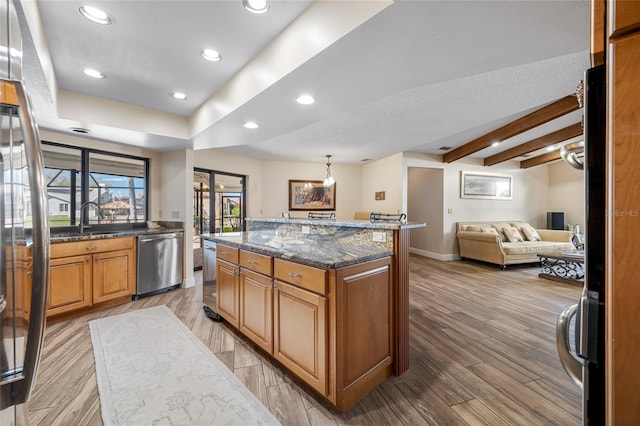 kitchen with a kitchen island, light wood-style flooring, a sink, dishwasher, and open floor plan