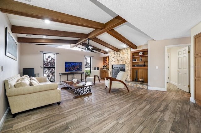 living room featuring light wood finished floors, vaulted ceiling with beams, a fireplace, ceiling fan, and a textured ceiling