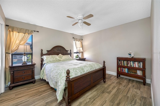 bedroom with baseboards, a textured ceiling, wood finished floors, and a ceiling fan