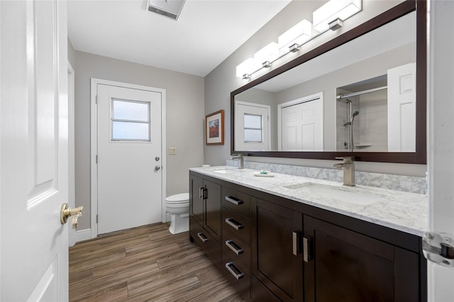 full bathroom with a shower with door, visible vents, wood finished floors, and a sink