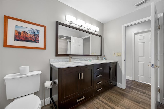 full bath with visible vents, toilet, a sink, wood finished floors, and baseboards