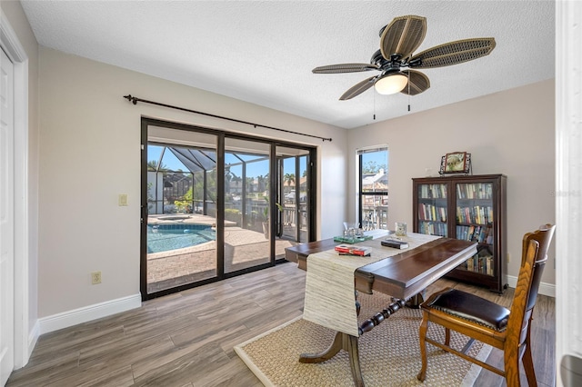 office with a ceiling fan, baseboards, light wood-style flooring, a sunroom, and a textured ceiling