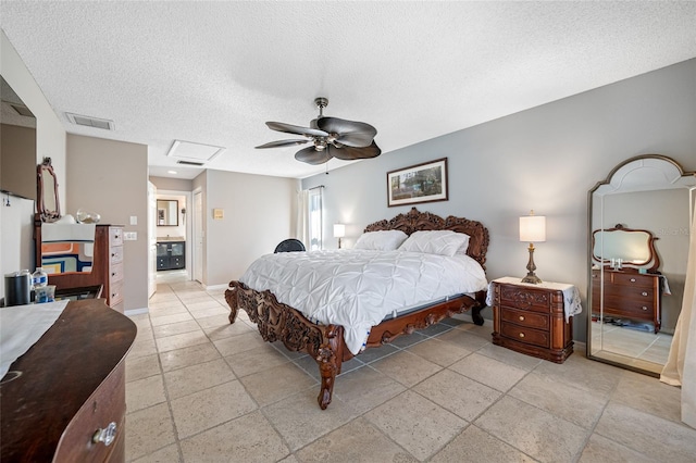 bedroom with baseboards, visible vents, attic access, ceiling fan, and a textured ceiling