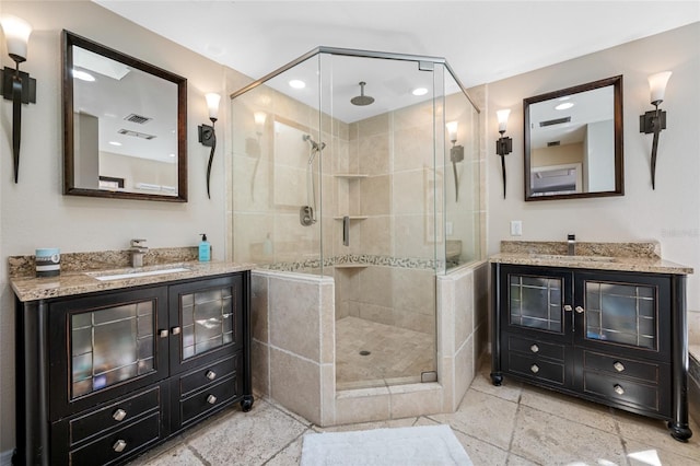 full bathroom featuring a shower stall, two vanities, and a sink