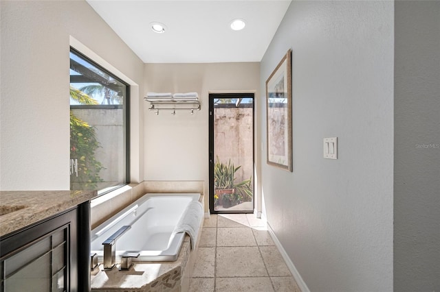 full bathroom featuring a bath, recessed lighting, baseboards, and stone tile flooring