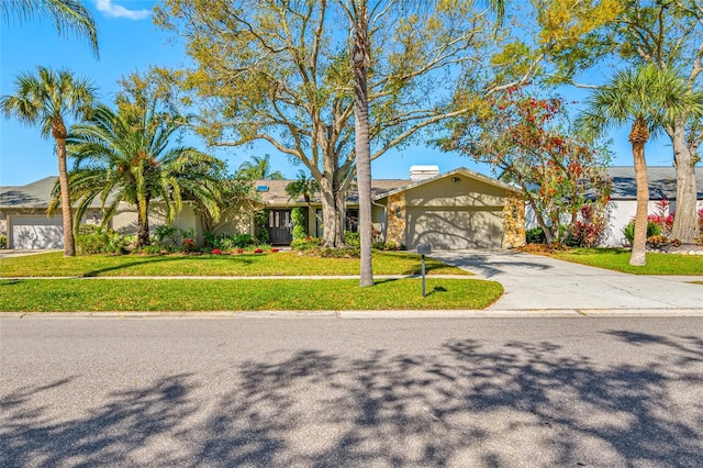 view of front of home with a front lawn, stucco siding, a garage, stone siding, and driveway