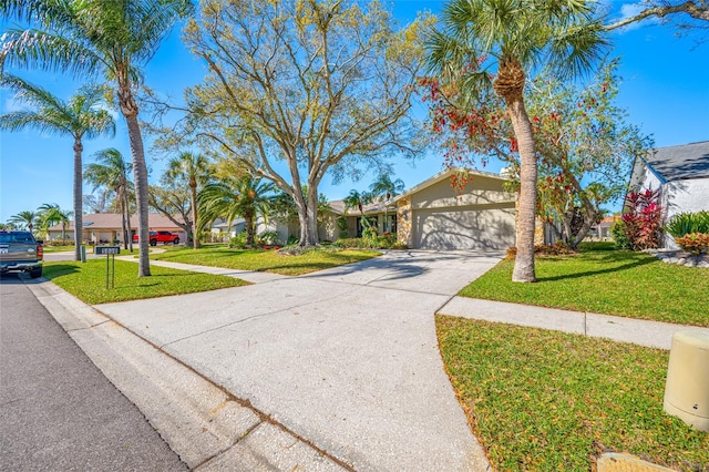 view of front facade with a garage, concrete driveway, a front yard, and stucco siding