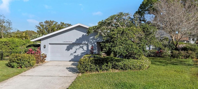 view of front of property with concrete driveway, an attached garage, a front lawn, and stucco siding