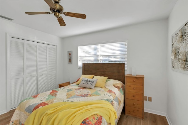 bedroom featuring visible vents, a ceiling fan, wood finished floors, a closet, and baseboards