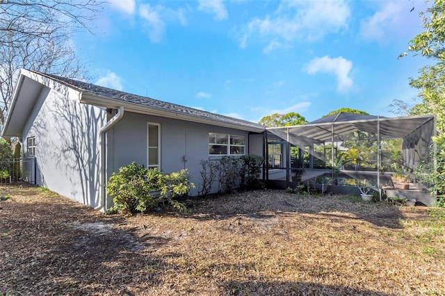 view of property exterior featuring glass enclosure and stucco siding