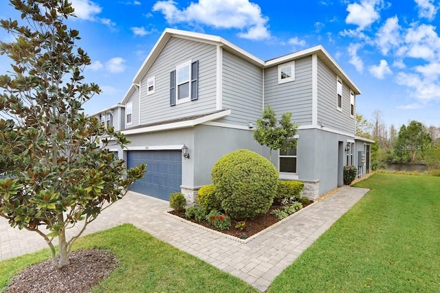 view of property exterior featuring stucco siding, decorative driveway, a garage, and a yard