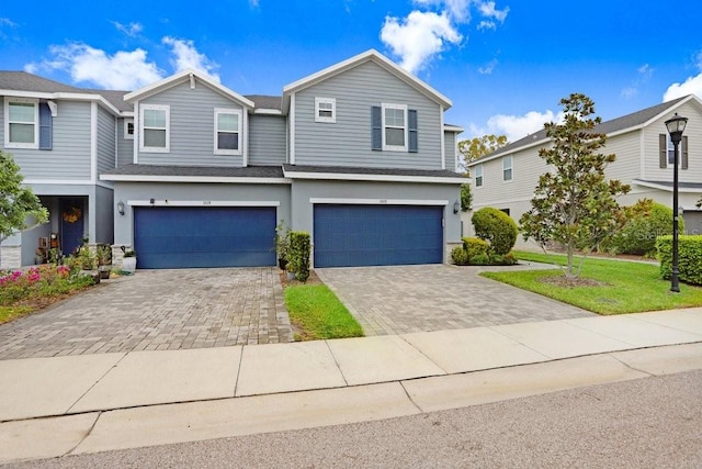 view of front of property with a front lawn, roof with shingles, stucco siding, decorative driveway, and a garage