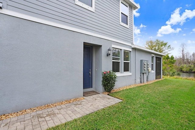 entrance to property with stucco siding and a lawn