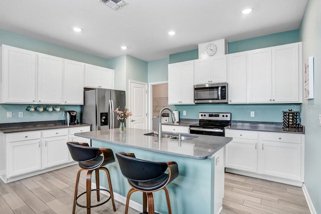 kitchen with a sink, stainless steel appliances, visible vents, and light wood finished floors