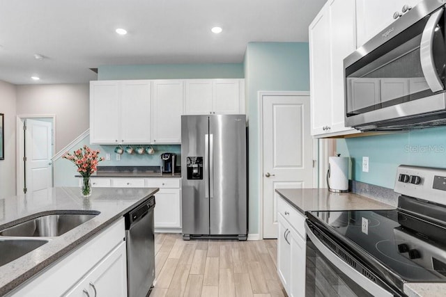 kitchen with dark stone counters, light wood-style flooring, recessed lighting, stainless steel appliances, and white cabinetry