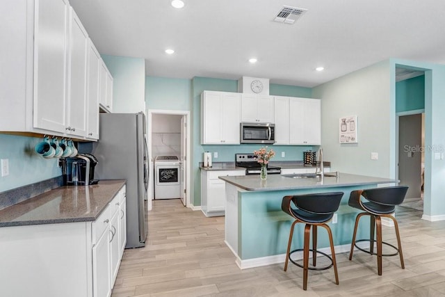 kitchen with a breakfast bar area, visible vents, washer / clothes dryer, a sink, and appliances with stainless steel finishes