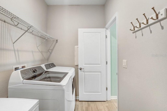 laundry room with light wood-style floors, separate washer and dryer, and laundry area