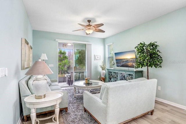 living area with baseboards, a ceiling fan, and wood finished floors