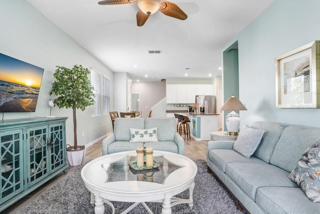 living room with visible vents, baseboards, recessed lighting, light wood-style floors, and a ceiling fan