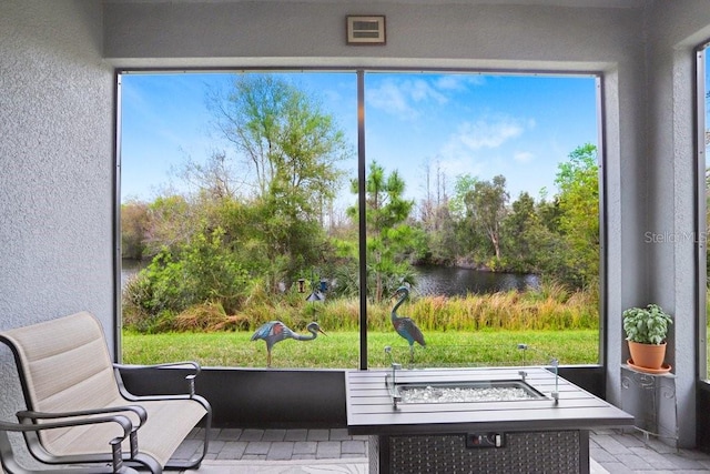 sunroom featuring a water view