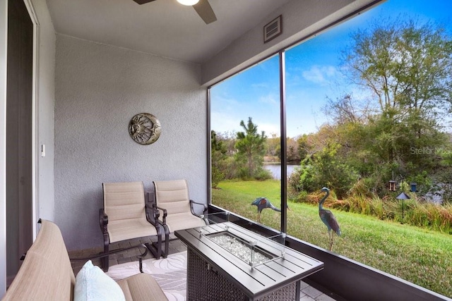 sunroom / solarium with visible vents, a ceiling fan, and a water view