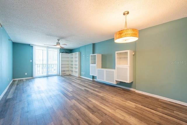 unfurnished living room featuring a textured ceiling, baseboards, and wood finished floors