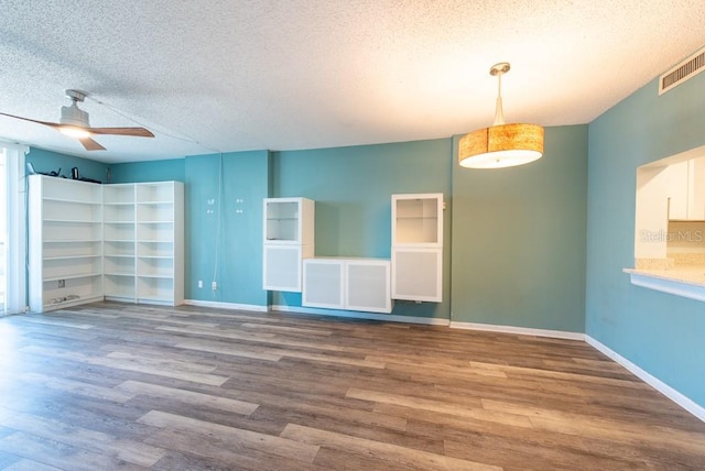 spare room featuring visible vents, a textured ceiling, wood finished floors, and a ceiling fan