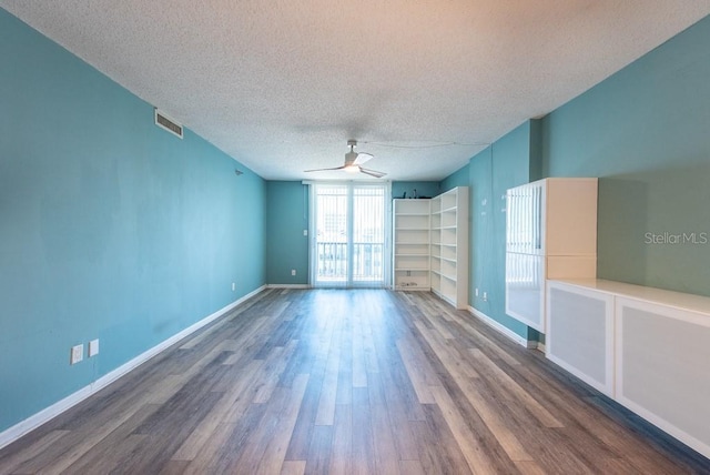 spare room featuring visible vents, baseboards, ceiling fan, wood finished floors, and a textured ceiling