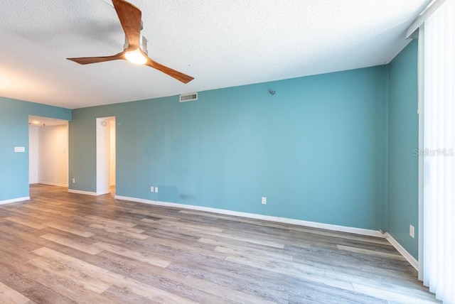 spare room with a ceiling fan, baseboards, wood finished floors, visible vents, and a textured ceiling