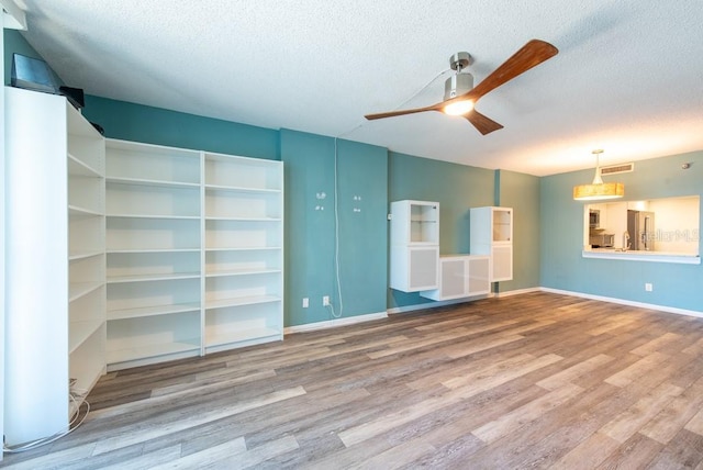 interior space featuring wood finished floors, baseboards, visible vents, ceiling fan, and a textured ceiling