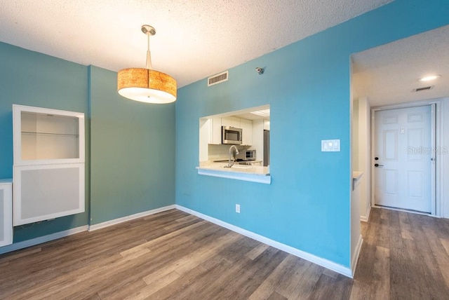 interior space with dark wood-style floors, visible vents, a textured ceiling, and baseboards