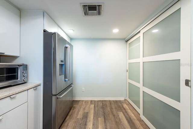 kitchen featuring visible vents, wood finished floors, stainless steel fridge, a toaster, and light countertops