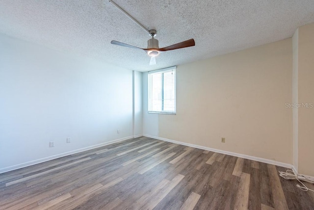 empty room featuring ceiling fan, a textured ceiling, baseboards, and wood finished floors