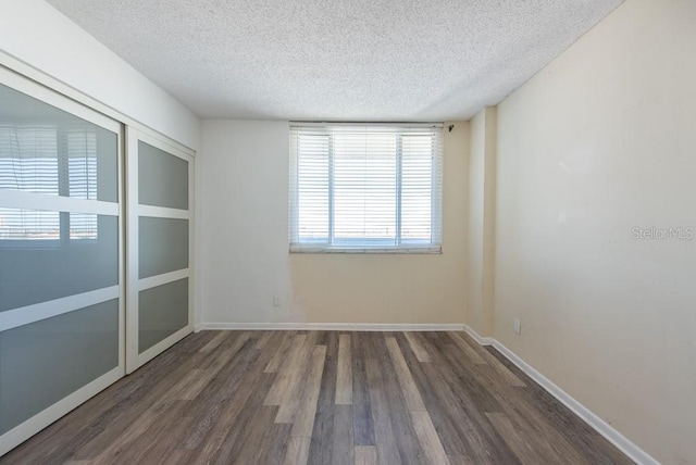 unfurnished room with baseboards, a textured ceiling, and wood finished floors