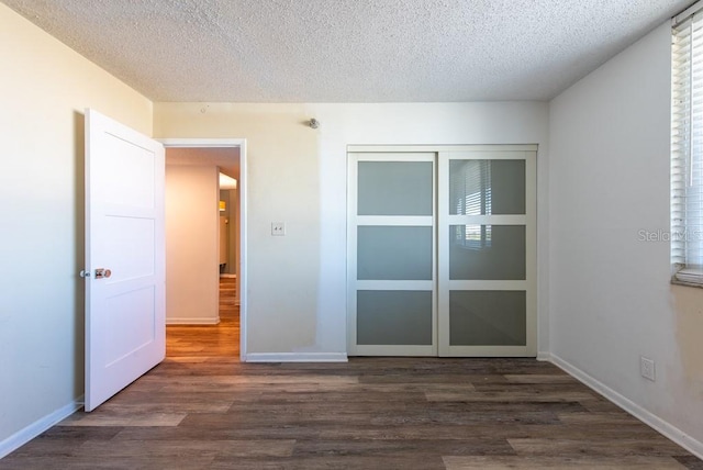 spare room featuring dark wood finished floors, a textured ceiling, and baseboards