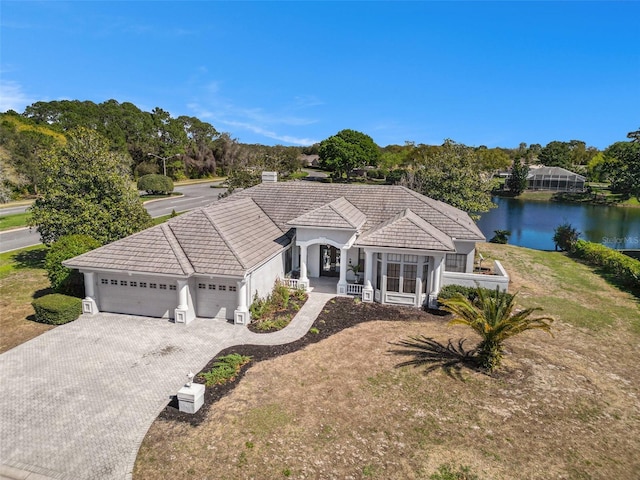 view of front of home featuring a water view, decorative driveway, covered porch, a garage, and a tiled roof