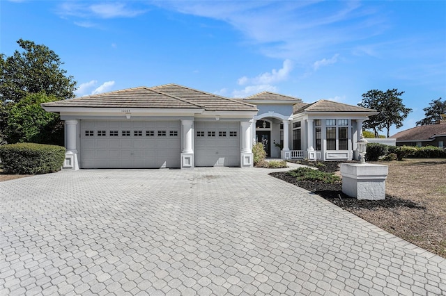 view of front of home featuring decorative driveway, stucco siding, an attached garage, and a tile roof