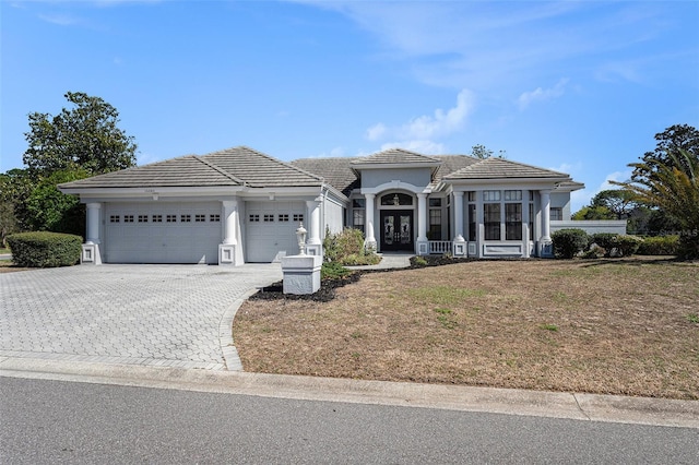 view of front of house with stucco siding, decorative driveway, french doors, a garage, and a tiled roof